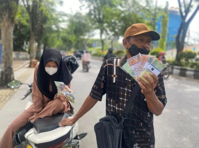 USAHA MUSIMAN: Daus menawarkan uang kertas baru di tepi Jalan Lambung Mangkurat, depan gedung DPRD Kalsel, Senin (17/4). | FOTO: M OSCAR FRABY/RADAR BANJARMASIN