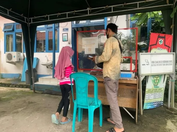 MENDAFTAR: Petugas Puskesmas Pemurus Dalam melayani seorang warga yang akan berobat. | Foto: Wahyu Ramadhan/Radar Banjarmasin