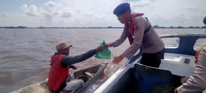 SAMBANGI NELAYAN: Sembari menyampaikan imbauan bahaya setrum ikan, personel Satpolairud Polres Batola memberikan paketan sembako kepada nelayan di Sungai Barito. | Foto: Maulana/Radar Banjarmasin