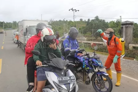 PENGAWASAN: Kendaraan dan orang menuju Tanjung Selor dari arah Berau harus melewati petugas untuk penyemprotan disinfektan dan pendataan. FOTO: PIJAI PASARIJA/RADAR KALTARA