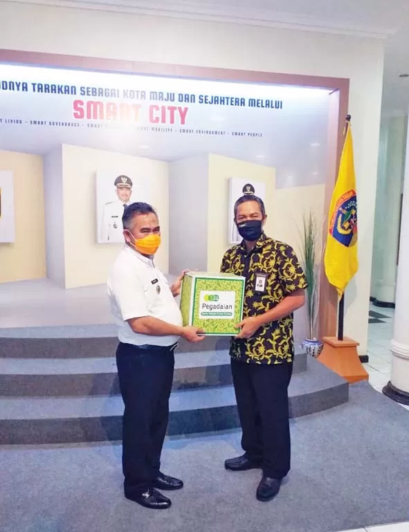 DISTRIBUSI: Nyoto Margono, Vice President PT Pegadaian (Persero) Area Kalimantan Utara (kanan) saat menyerahkan bantuan secara simbolis kepada Wali Kota Tarakan dr.Khairul. M.Kes. FOTO: IST