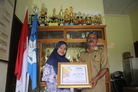 BERPRESTASI: Kika Putri Sari didamping Kepala SMPN 2 Tanjung Selor memperlihatkan piagam juara lomba dakwah online tingkat nasional./PIJAI PASARIJA/RADAR KALTARA