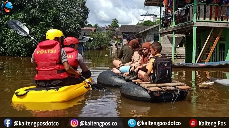 Anggota kepolisian dari Polres Murung Raya membantu sejumlah anak sekolah di Desa Beriwit untuk melalui banjir yang merendam desa mereka, Sabtu (7/3/2020)
