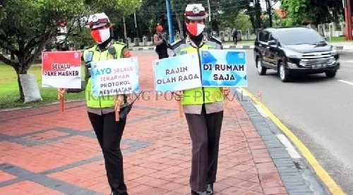 Dua anggota Polwan menunjukkan papan imbauan kepada warga di bundaran besar, Palangka Raya.