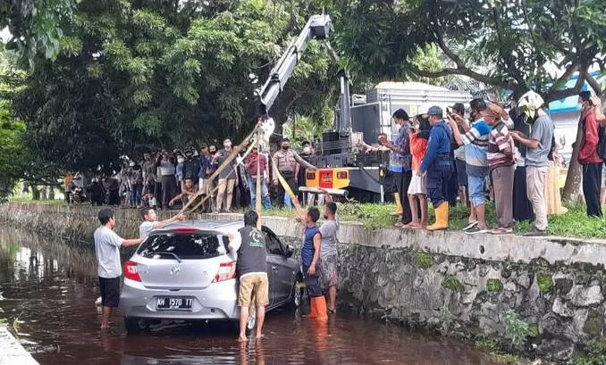 Sebuah mobil tercebur ke drainase di Jalan Nyai Undang, Palangka Raya, Sabtu (1/1/2022), sedang dievakuasi. (HAFIDZ/PROKALTENG.CO)