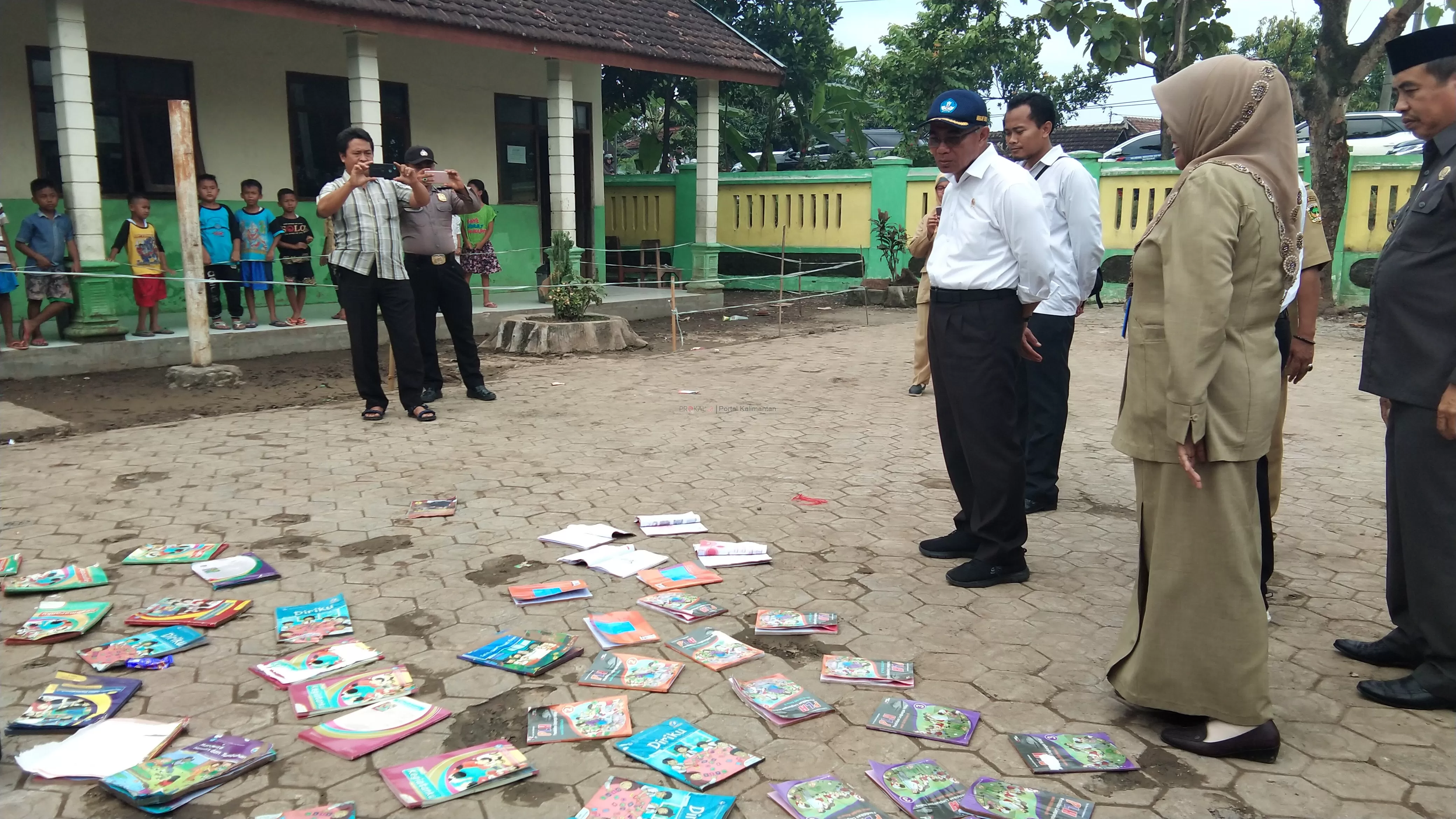Mendikbud Muhadjir Effendy melihat buku-buku pelajaran milik sekolah dan siswa yang dijemur di lapangan SDN Purworejo 01 akibat terendam banjir. (Foto : nicha / kaltim post)