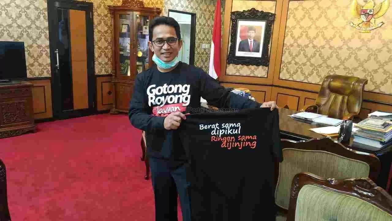GERAKAN BERSAMA -  Rahmad Mas’ud memperlihatkan baju kaus hitam bertuliskan Gotong Royong Lawan Corona. (foto: dok RMC)