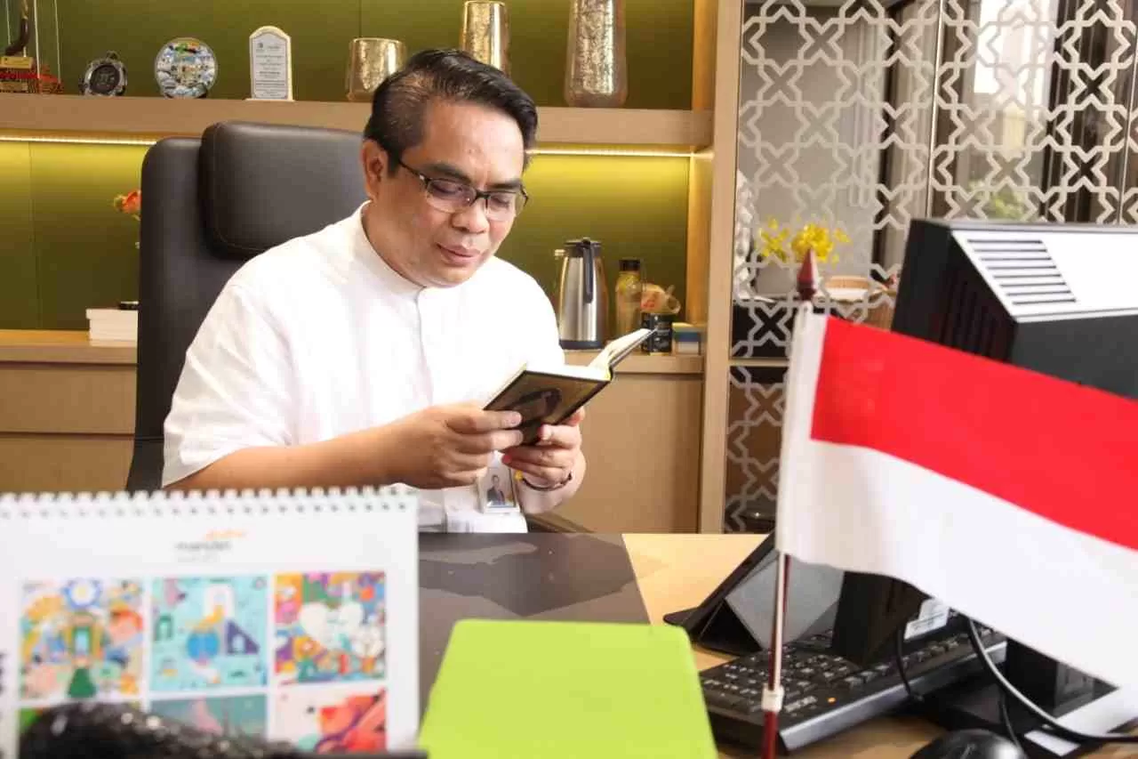 JUMAT BERKAH: Di tengah kesibukan kantor pusat, Anton Sukarna, membaca Alquran sekaligus berdoa di meja kerjanya.