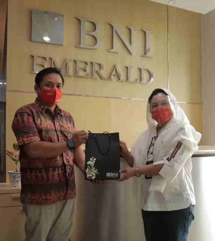 HARI PELANGGAN NASIONAL: Catur Sri Rejeki (kanan) memberikan souvenir kepada salah satu pelanggan yang bertransaksi di kantor cabang BNI Balikpapan.