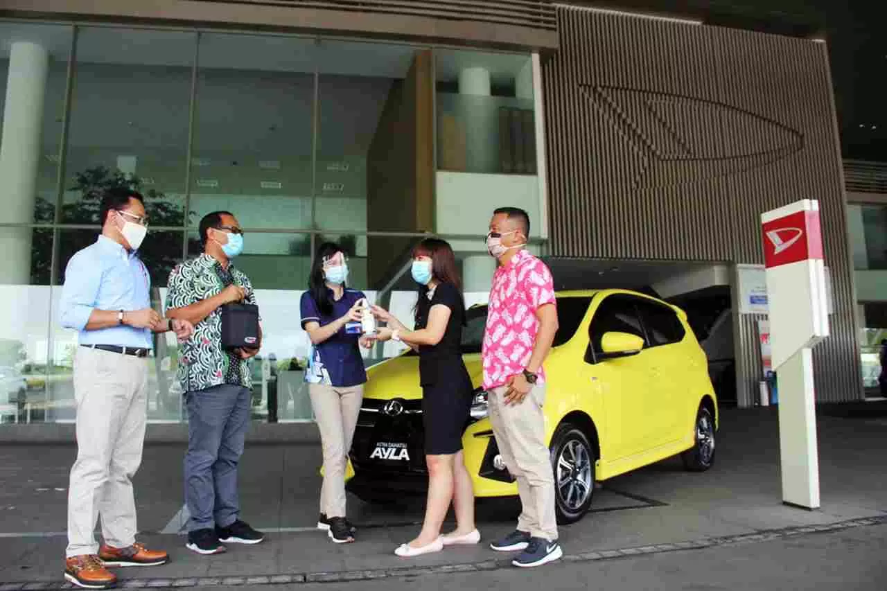 PERKUAT KOMITMEN: Hendrayadi Lastiyoso (kiri) menyaksikan penyerahan disinfektan dari marketing (tengah) kepada konsumen yang membeli mobil Daihatsu baru, di BSD City, Tangerang Selatan, Selasa (15/9/2020).