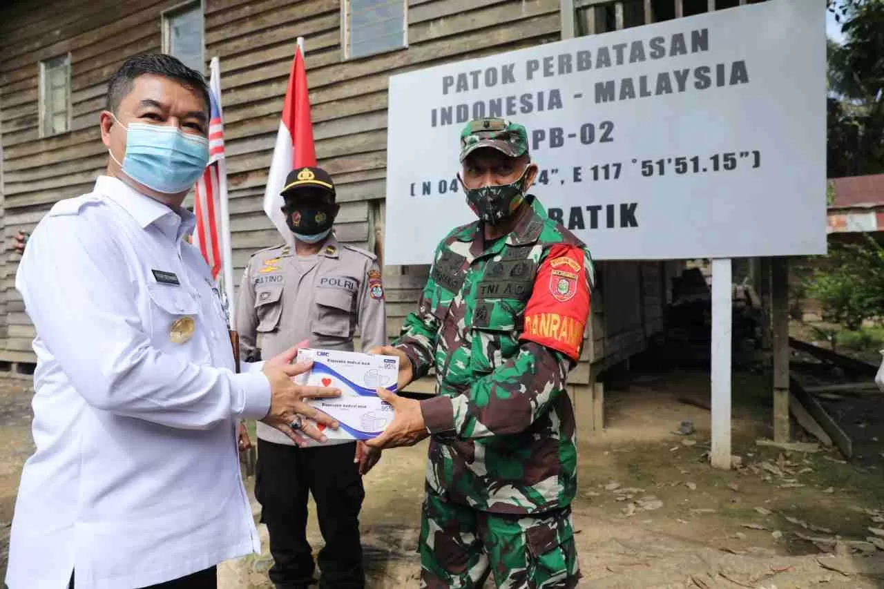 PATUHI PROTOKOL KESEHATAN: Pjs Gubernur Kaltara Teguh Setyabudi menyerahkan masker kepada aparat keamana di perbatasan.