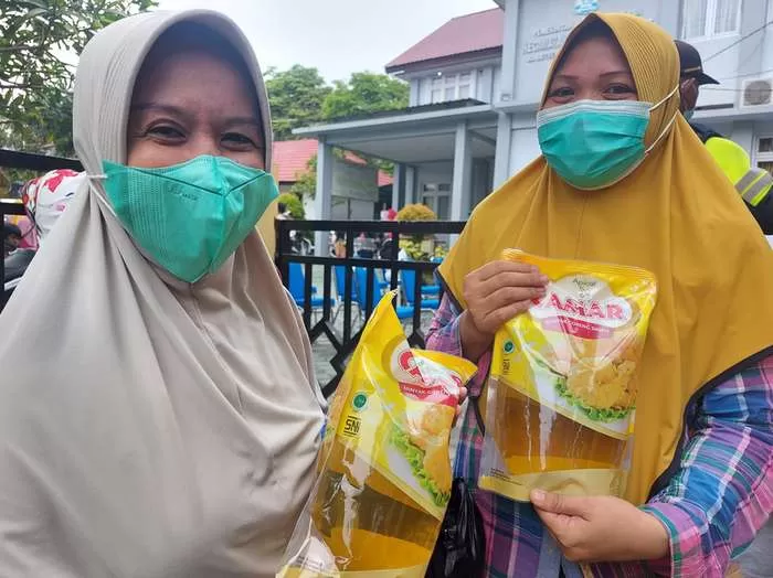 DISAMBUT BAIK : Siti Rahma dan Masliana menyambut baik operasi pasar minyak goreng yang digelar di Halaman Kecamatan Balikpapan Barat, Rabu (29/12).