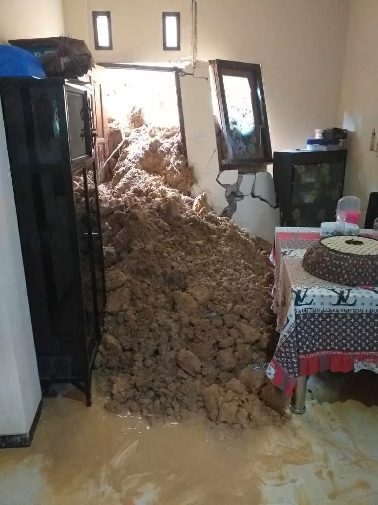 TERTIMPA LONGSOR: Warga membersihkan sisa-sisa tanah longsor yang menerjang rumah miliknya akibat hujan dengan intensitas tinggi, kemarin (6/5).