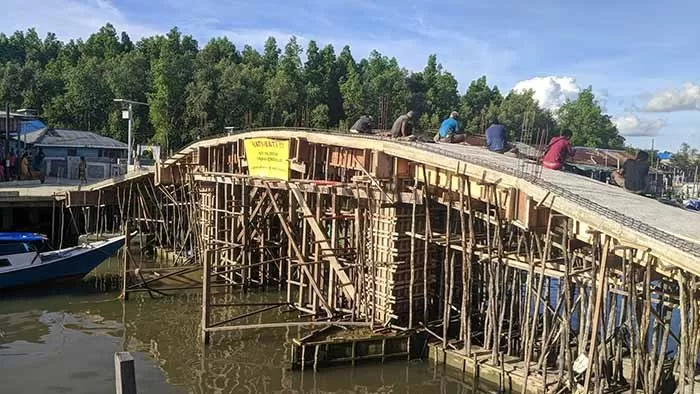 TELAH DIRAMPUNGKAN: Beberapa pekerja masih melakukan aktivitas meski sudah dilakukan pengecoran terhadap jembatan yang sempat ambruk, Jumat (8/1).