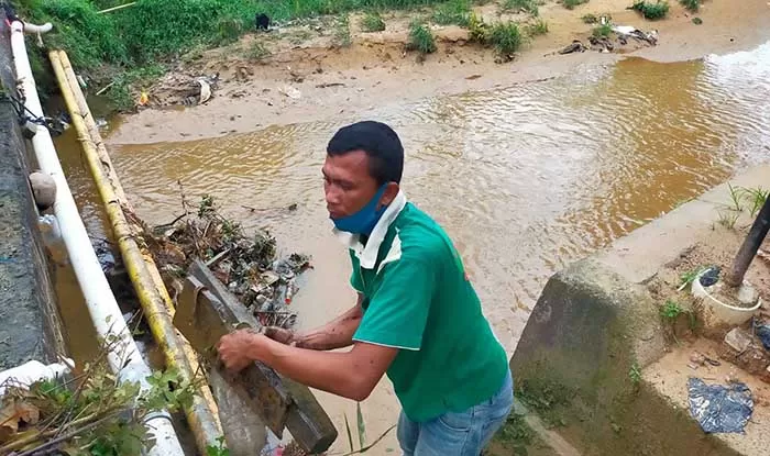 BERSIHKAN LIMBAH: Petugas membersihkan tumpahan oli bekas yang mencemari sungai Kampung Bugis.