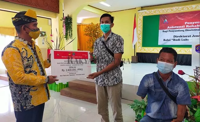 SALURKAN BANTUAN: Wali Kota Tarakan Khairul (kiri) menyerahkan bantuan ATENSI kepada penyandang disabilitas di gedung Serbaguna Kantor Wali Kota Tarakan, Kamis (2/12).
