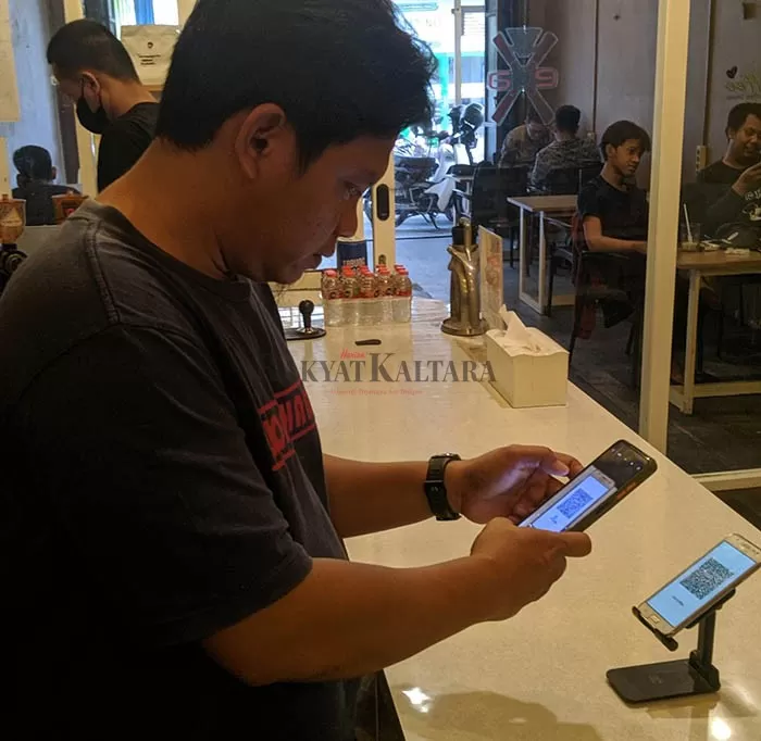 PENGGUNA QRIS: Salah seorang pengunjung melakukan transaksi menggunakan QRIS disalah satu coffee shop di Tarakan, Kamis (1/9).