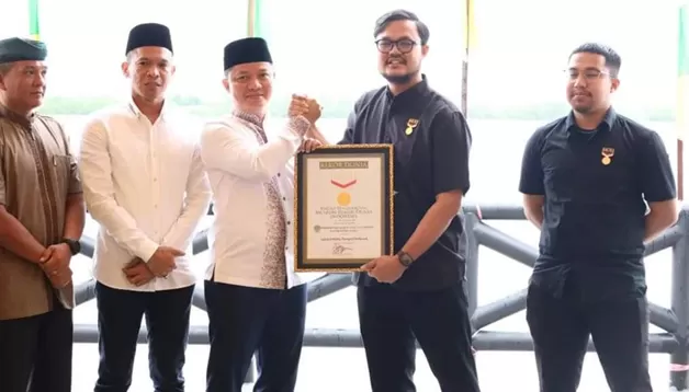 RAIH REKOR MURI: Bupati KTT Ibrahim Ali (tiga dari kiri) menerima penghargaan rekor MURI untuk penyajian sebanyak 67.693 ribu ketupat dalam tradisi tolak bala, Rabu (21/9).
