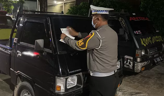 DIPASANGI STIKER: Personel Satlantas Polres Tarakan memasang stiker imbauan di mobil masyarakat agar  mengantre BBM saat jam operasional SPBU.