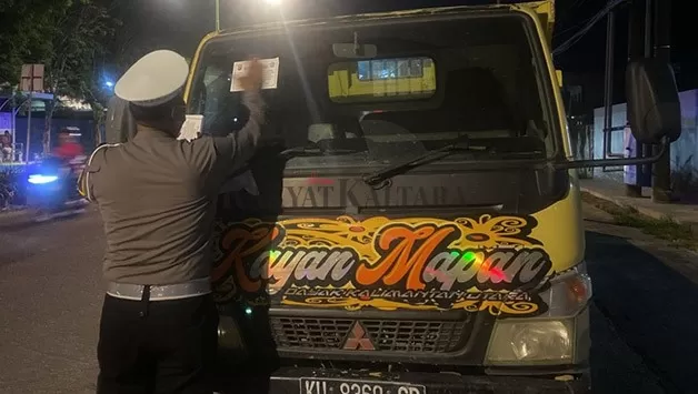 DITINDAK: Personel Satlantas Polres Tarakan memasang stiker peringatan terhadap truk yang menginap untuk mengisi BBM di SPBU.