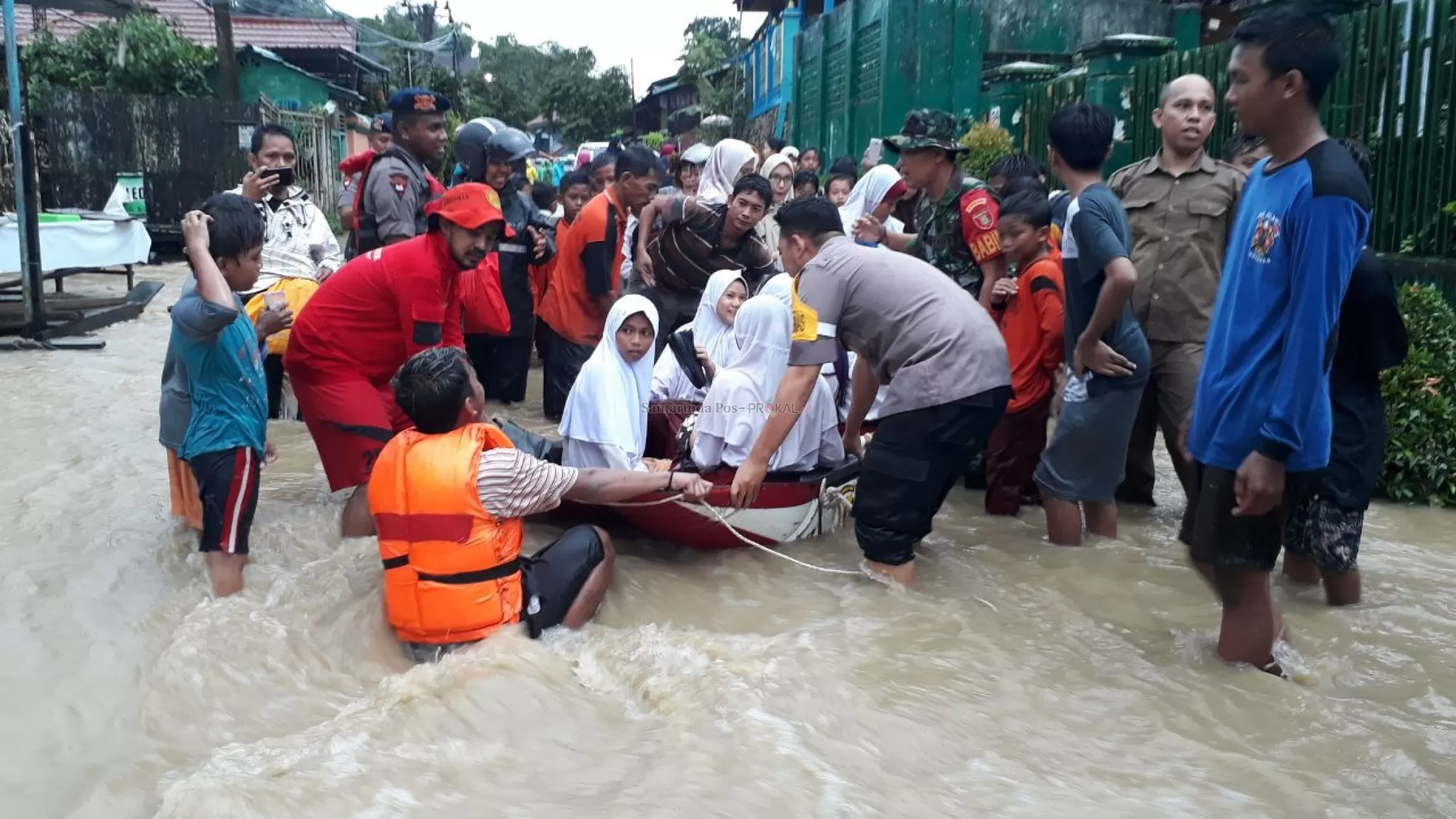 Petugas mengevakuasi murid SD dalam banjir di Samarinda.