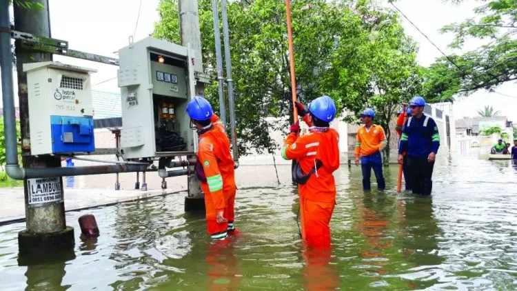 Petugas PLN memadamkan sementara listrik karena gardu nyaris tenggelam.