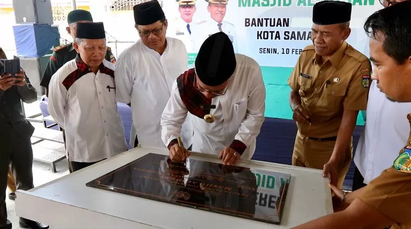 BANTUAN WARGA. Syaharie Jaang disaksikan wali kota Palu (baju cokelat) saat menandatangani prasasti peresmian Masjid Al-Ihsan.