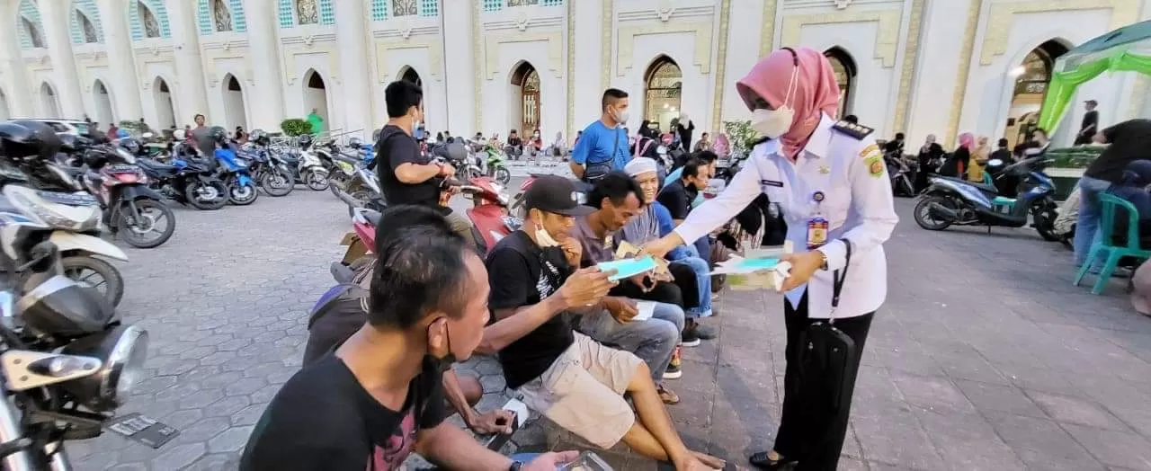 WAJIB PROKES. Warga yang berkunjung ke Masjid Raya Darussalam diberikan masker dan diimbau, terkait bahaya penularan virus korona.