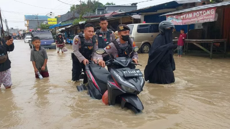 DORONG MOTOR. Personel patroli beat 110 Polresta Samarinda bantu pengendara motor yang mengalami mogok saat melintas di area banjir. (kis)