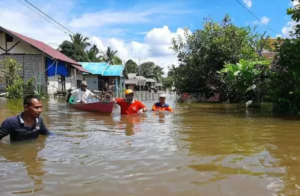 EVAKUASI : Plt Kepala BPBD Tengku Alisyahbana bantu evakuasi lansia saat banjir melanda Desa Rungun, Kecamatan Kotawaringin Lama. (BPBD KOBAR /RADAR PANGKALAN BUN )