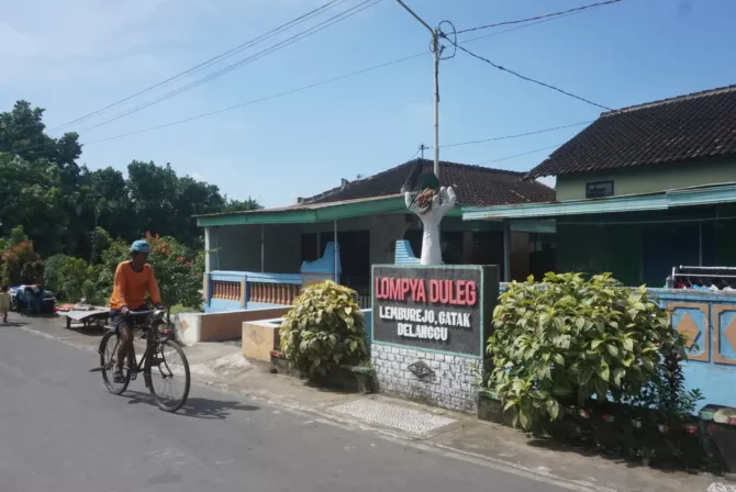 PENANDA: Pengendara melewati Tugu Lumpia Duleg yang ada di Dusun Lemburejo, Desa Gatak, Kecamatan Delanggu. (ANGGA PURENDA/RADAR SOLO)