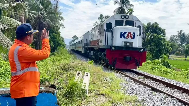 Seorang petugas PT KAI memberikan isyarat saat kereta api melintas di jalur rel kawasan pedesaan Sumatera Barat (Sumbar). (Dok. KAI)