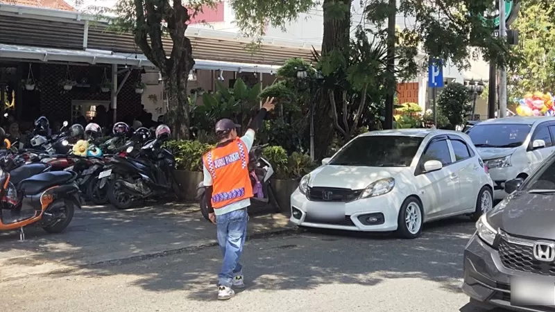 Seorang petugas parkir mengarahkan kendaraan pengunjung di kawasan pusat kuliner Kota Padang saat aktivitas masyarakat meningkat pada libur panjang akhir pekan. (Dok. Diskominfo Padang)