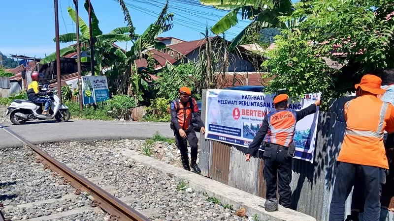 Petugas KAI Divre II Sumbar memasang spanduk imbauan keselamatan dan melakukan sosialisasi kepada masyarakat di perlintasan sebidang sebagai upaya meningkatkan keselamatan perjalanan kereta api selama masa libur sekolah. (Dok. KAI Divre II Sumbar)