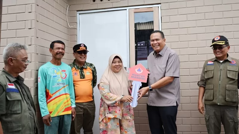 Sekretaris Utama (Sestama) Badan Nasional Penanggulangan Bencana (BNPB) Rustian bersama Wali Kota Pariaman Yota Balad menyerahkan kunci rumah kepada Emridona, warga terdampak bencana hidrometeorologi di Desa Sintuak, Kecamatan Pariaman Utara, Kota Pariaman, Jumat (10/7/2026). (Foto: Pemko Pariaman)