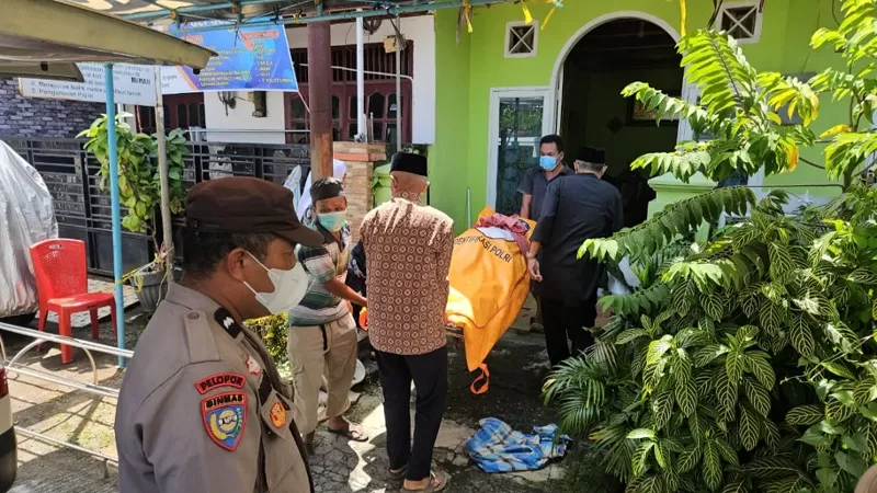 Petugas kepolisian mengevakuasi jasad perempuan berusia 71 tahun yang ditemukan meninggal dunia di dalam rumahnya di Komplek Cendana, Kelurahan Mata Air, Kecamatan Padang Selatan, Kota Padang, Rabu (22/7/2026) siang. Polisi masih menyelidiki penyebab pasti kematian korban. (Dok. Polresta Padang)