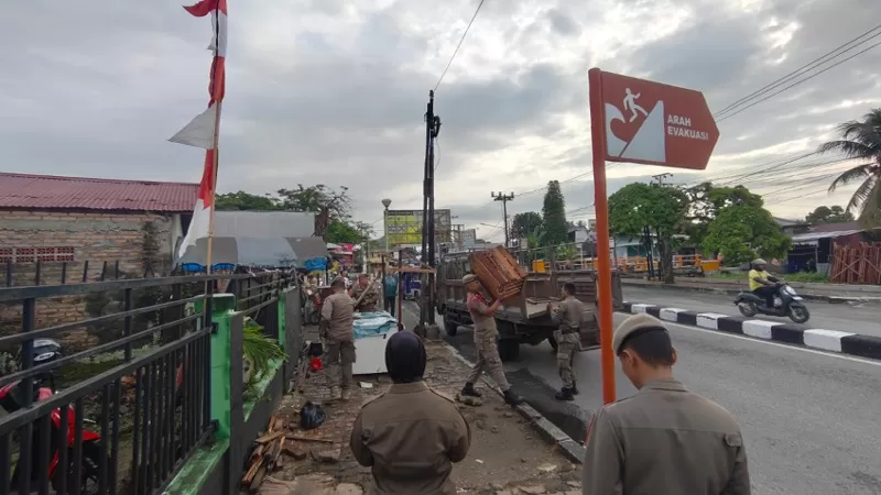 Petugas Satpol PP Kota Padang mengamankan sejumlah lapak PKL yang ditinggalkan di atas trotoar di kawasan Pasar Alai, depan Puskesmas Alai, Kecamatan Padang Utara, Senin (3/8/2026), sebagai upaya mengembalikan fungsi fasilitas umum dan menjaga ketertiban. (Dok. Humas)