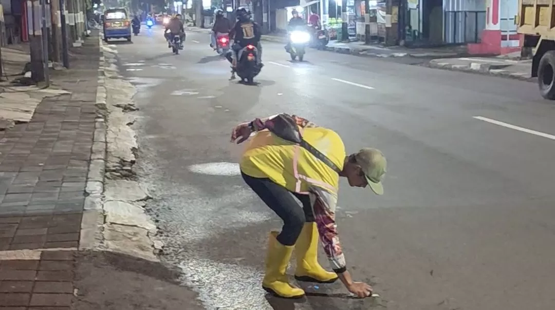 Potret Petugas DLHK Kabupaten Sumedang, Ridwan (24) sedang memungut sampah di Jalan Raya Prabu Geusan Ulun Sumedang, pada Kamis (1/1/2026) dini hari.