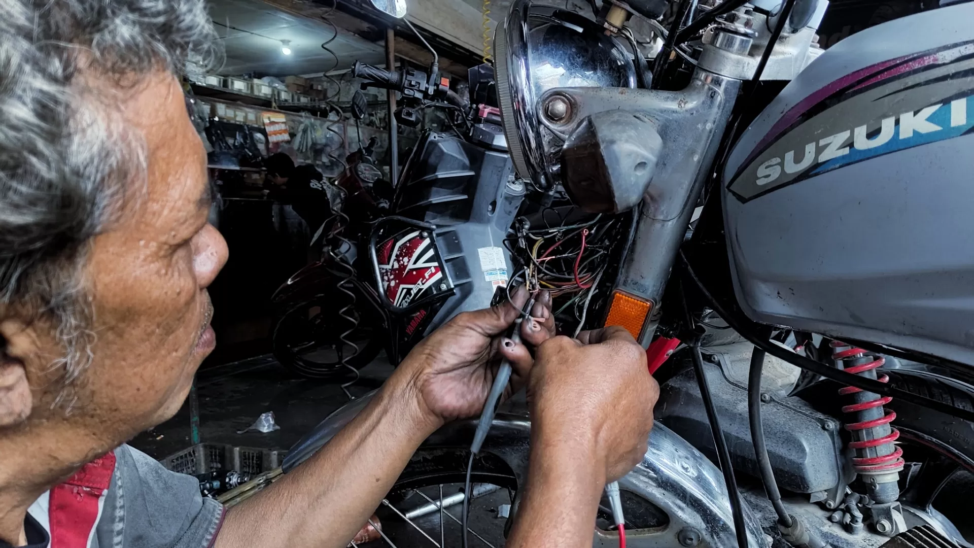 Potret Aki Dede, Mekanik Bengkel Sanjaya Motor Sumedang, sedang memperbaiki kelistrikan motor, Kamis (15/01/2026).
