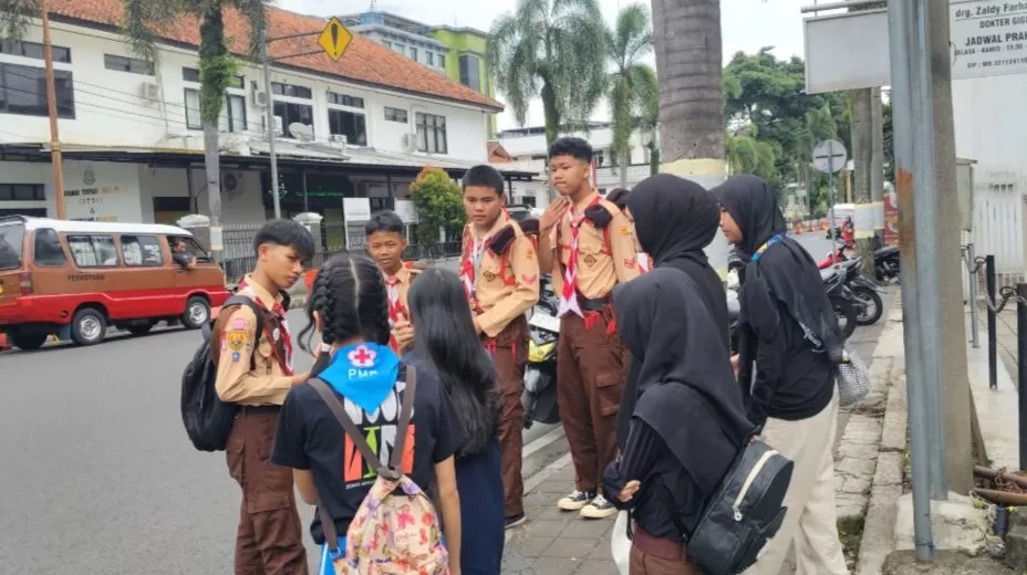 Potret salah satu Regu Pramuka sedang bertanya kepada para Anggota PMR di Pos penjagaan perempatan Kantor Kejaksaan Sumedang. Minggu (08/02/2026).
