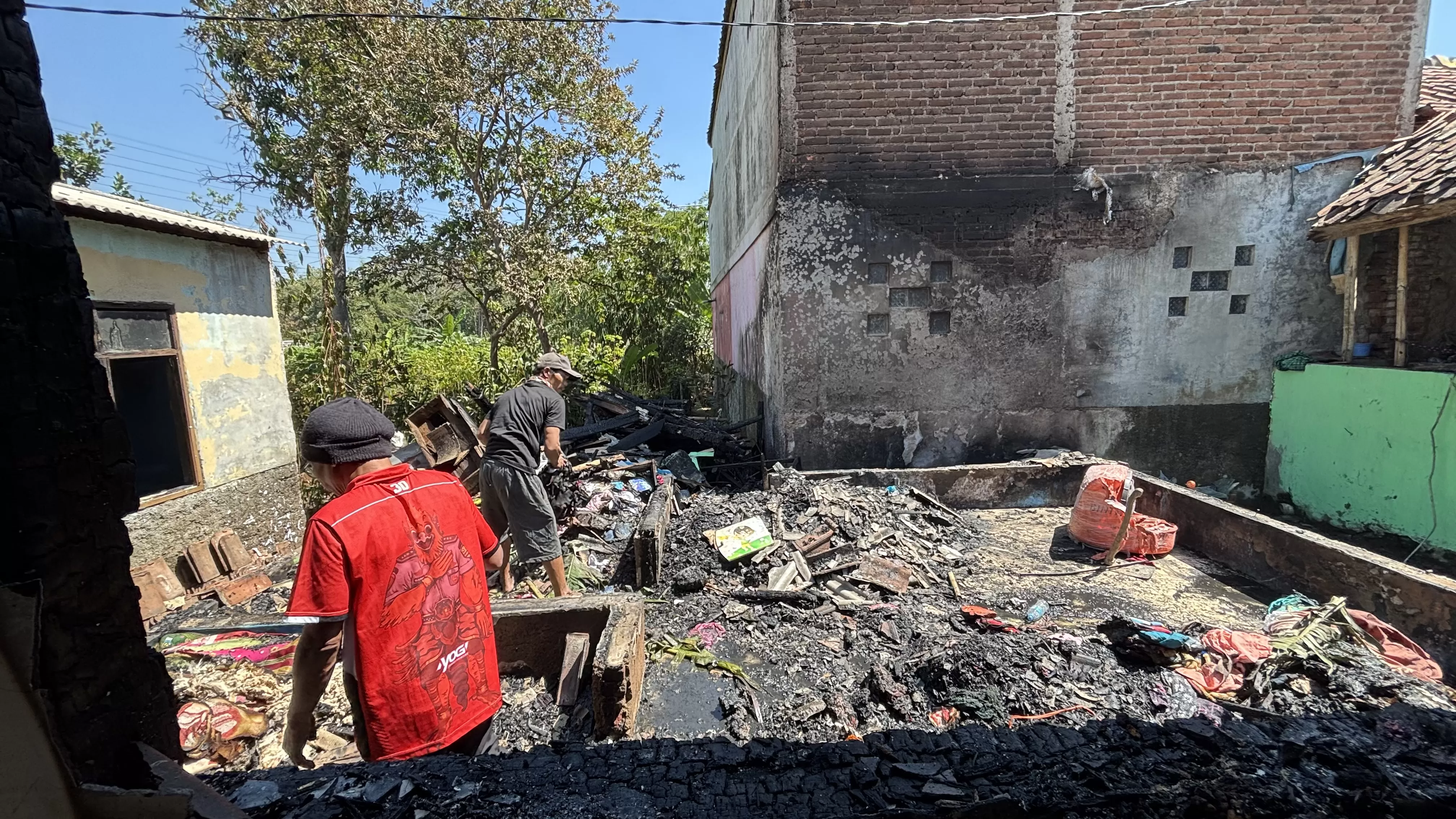 Warga membersihkan puing-puing rumah yang hangus terbakar di Dusun Cijaringao, Desa Cihanjuang, Kecamatan Cimanggung, Rabu (8/7/2026). 