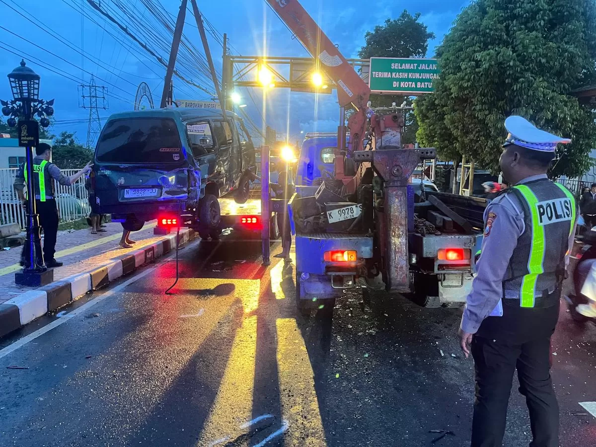 Anggota Unit Gakkum Sat Lantas Polres Batu yang dipimpin IPDA Agus Atang Wibowo melakukan pengukuran dan dokumentasi di lokasi kecelakaan. Terlihat dua unit sepeda motor Honda Beat yang hancur akibat terlindas truk.