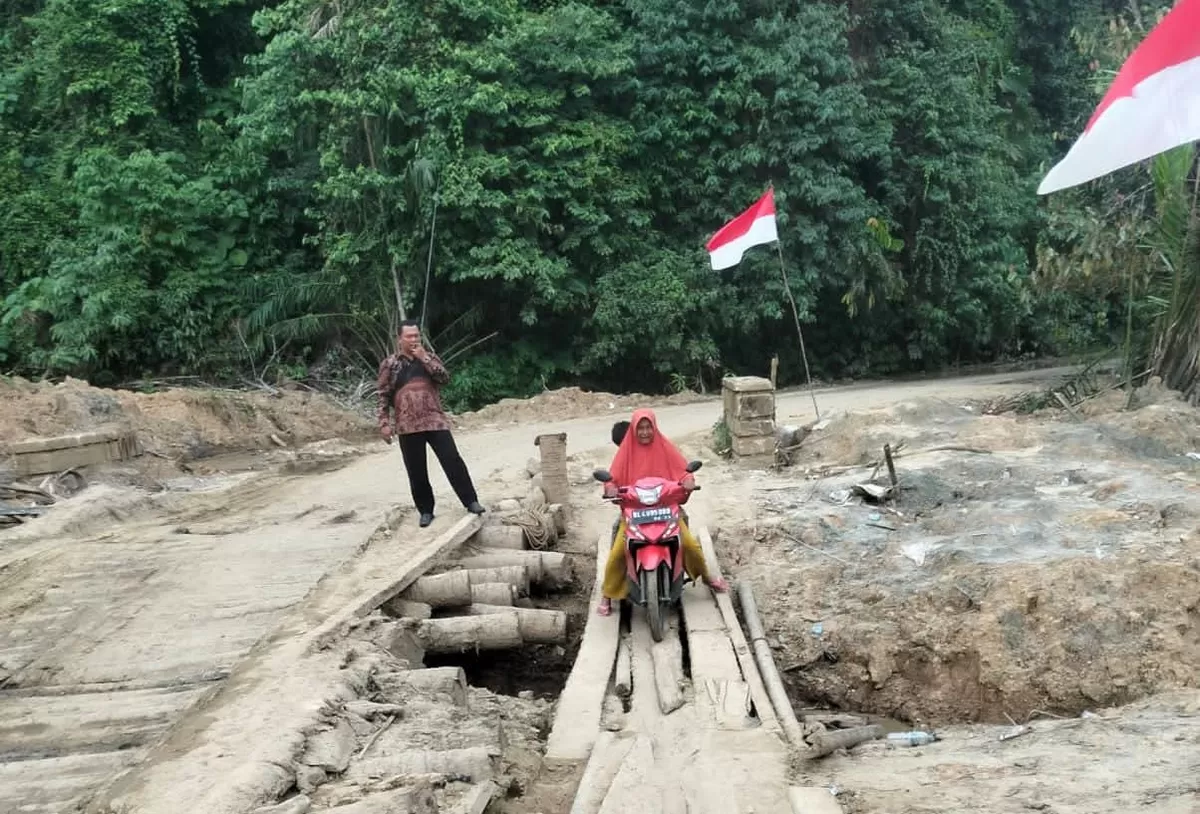 Camat Peunaron, Muhammad, meninjau jembatan darurat yang terbuat dari batang kelapa di Gunung Putus, Desa Peunaron Lama, Kecamatan Peunaron, Kabupaten Aceh Timur, baru-baru ini. Foto Humas Kantor Camat Peunaron