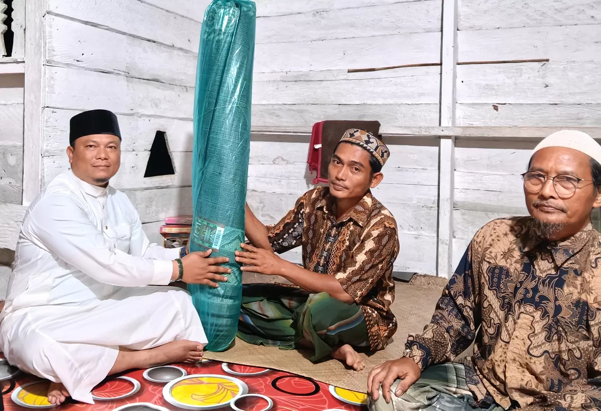 SERAHKAN SAJADAH: Camat Peunaron, H. Muhammad, S.Pd.I, MA, menyerahkan bantuan sajadah dan Alquran dari Bupati Aceh Timur ke Mushalla Al Hidayah, Gampong Sri Mulya, Kecamatan Peunaron, Kabupaten Aceh Timur, Senin (3/2). Foto Dok. Kantor Kecamatan Peunaron