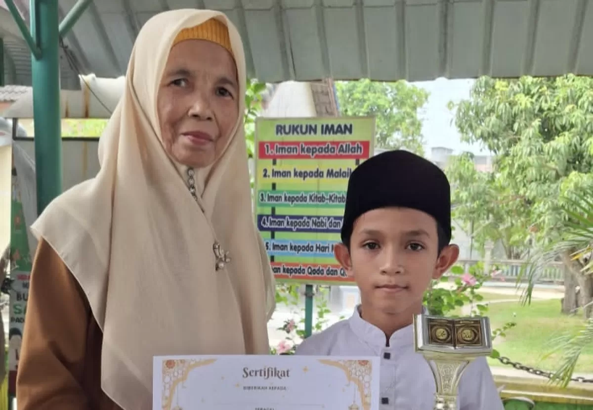 Rosmawardani Kepsek SDN 1 Idi Rayeuk, menyerahkan piala dan sertifikat penghargaan kepada peserta peraih juara kegiatan Dinul Islam selama Ramadhan di sekolah setempat.
