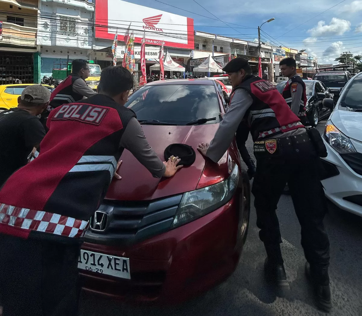 Personel Unit Patroli Presisi Sat Samapta Polres Bulukumba saat mengevakuasi mobil mogok di jalur dua depan Pasar Sentral Bulukumba, Senin (6/4/2026).