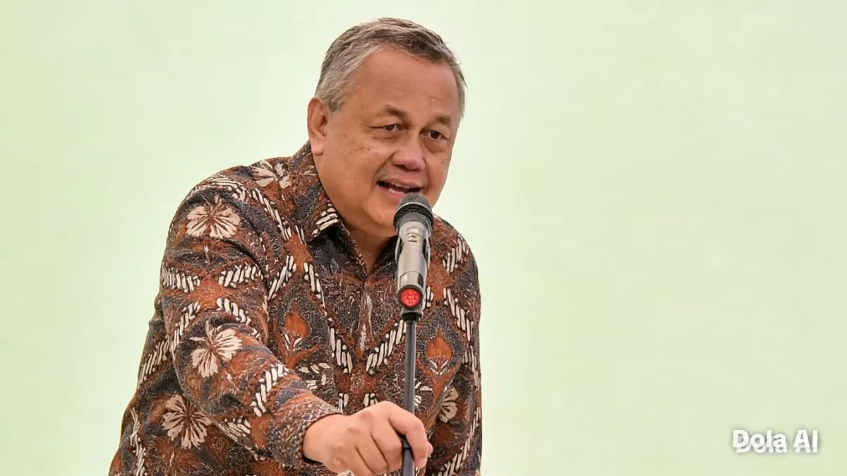 Pergerakan rupiah menuju Rp18.000 per Dolar AS menjadi sorotan setelah PEPS mengingatkan risiko tekanan ekonomi struktural Indonesia. Gubernur BI Perry Warjiyo (Dok. Hallo.id /Kreasi Dola AI)