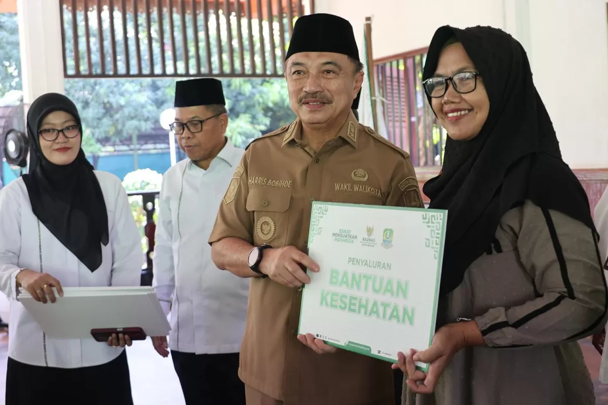 Plh Wali Kota Bekasi, Abdul Harris Bobihoe, saat menyerahkan bantuan kepada salah satu warga. (mame/metropolitan)