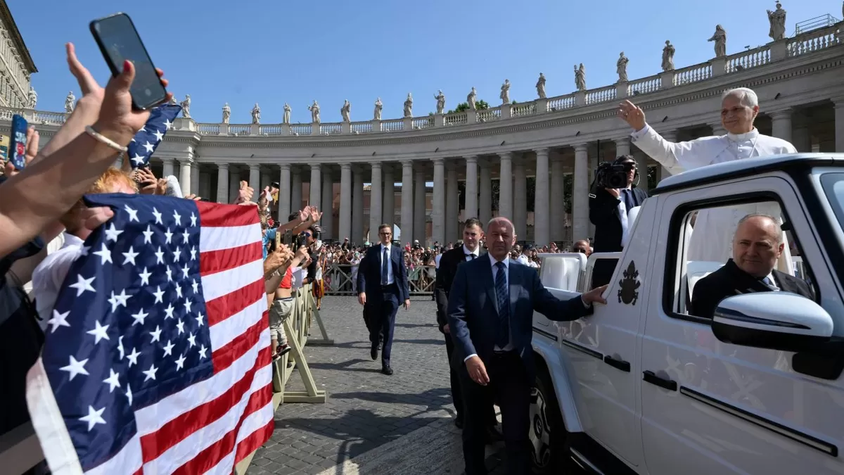 Paus Leo XIV melambaikan tangan kepada para peziarah yang memegang bendera Amerika Serikat saat ia tiba di Lapangan Santo Petrus dengan popemobile untuk audiensi umum di Vatikan pada 18 Juni 2025.