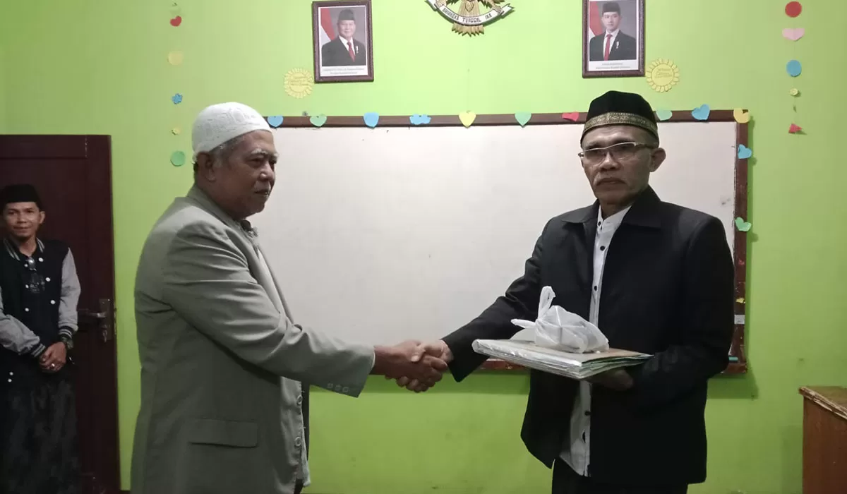 Ketua DKM lama Nurul Barkah Kampung Sukagalih Kelurahan Talagasari Kecamatan Kawalu Kota Tasikmalaya Nana Suryana secara simbolis menyerahkan estafet kepengurusan kepada Ketau DKM baru H Jenal Aripin di Madrasah Nurul Barkah, Selasa (17/02/2026). (Dok. Asep M.S)